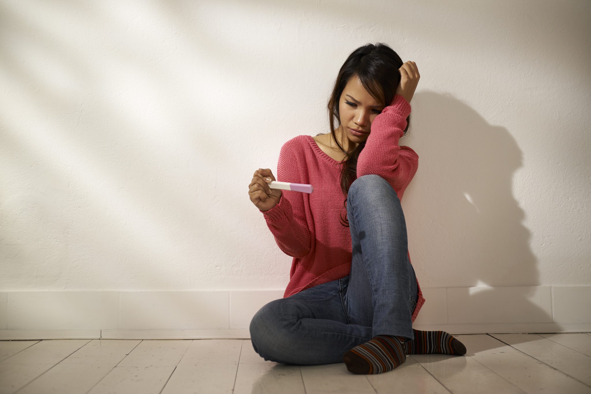 Stressed young woman looking at a pregnancy test