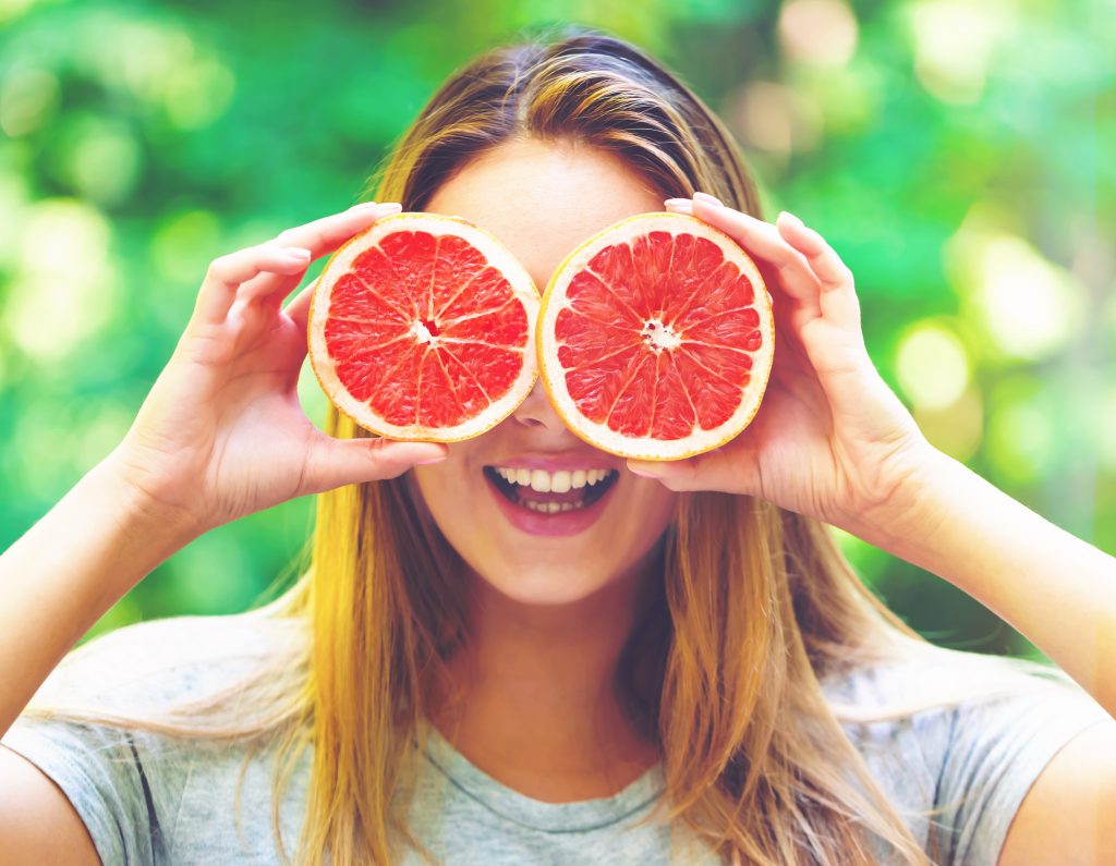 Woman holding grapefruits up to her face