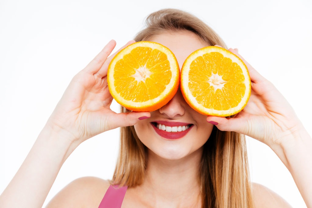 Woman holding oranges up to her face