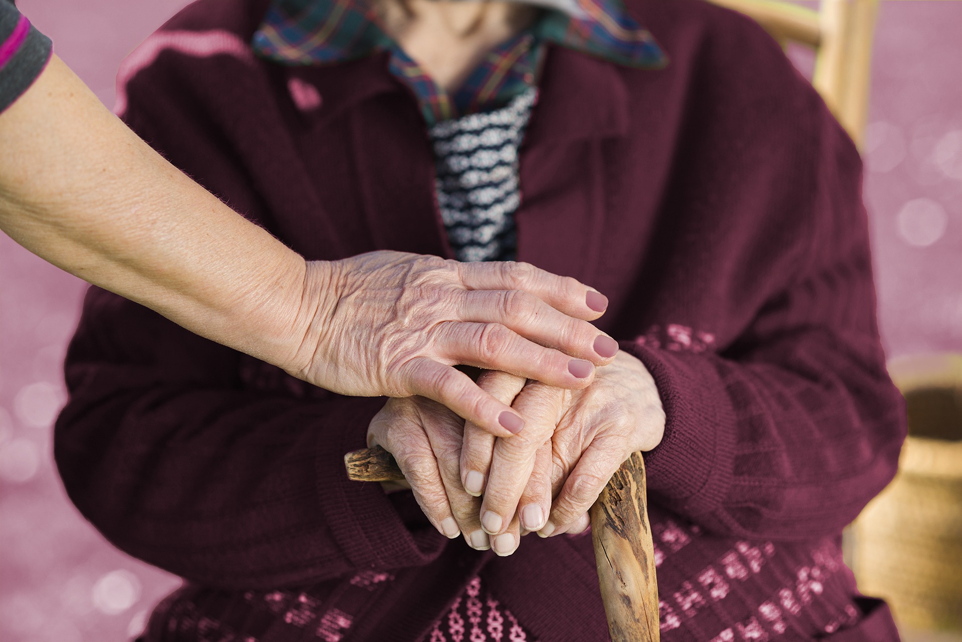 Older woman hands rested on a wood cane