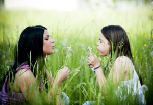 Mom and daughter blowing flowers in a field