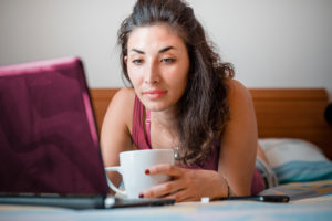 Woman with coffee in front of laptop